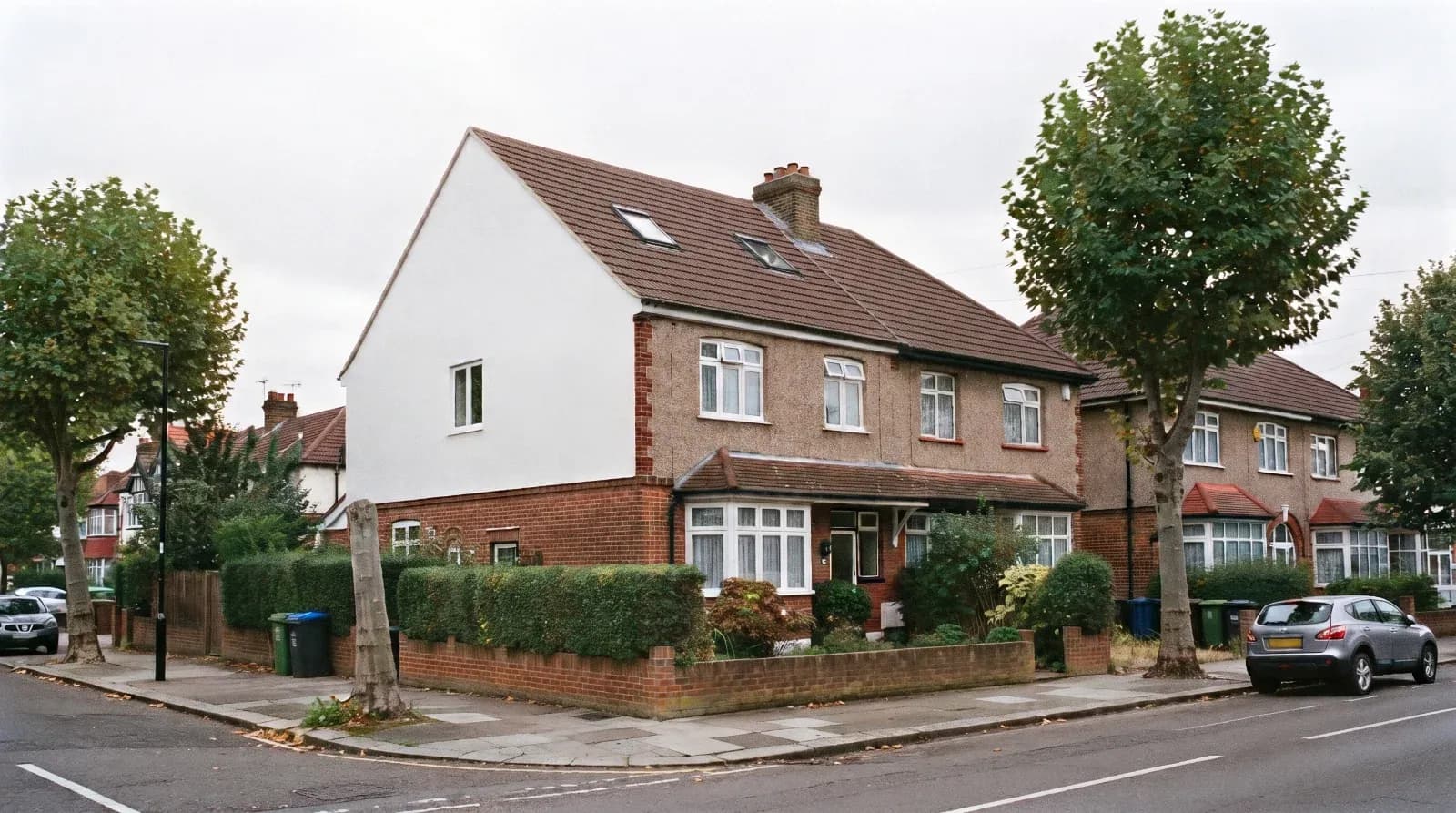 Semi-detached brick house with white rendered dormer and brown tiled roof, showing completed loft conversion with extend